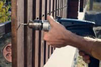 contractor's hands power drilling wood fence boards to metal structure